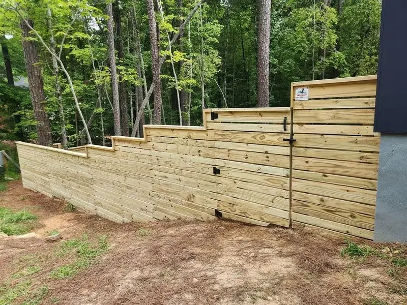 Finished stepped horizontal-board privacy fence with a gate, following a slope