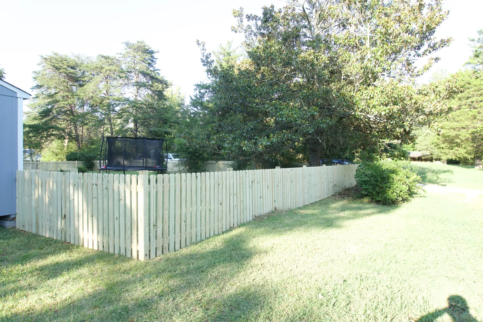 Wood picket fence running along the side of a back yard