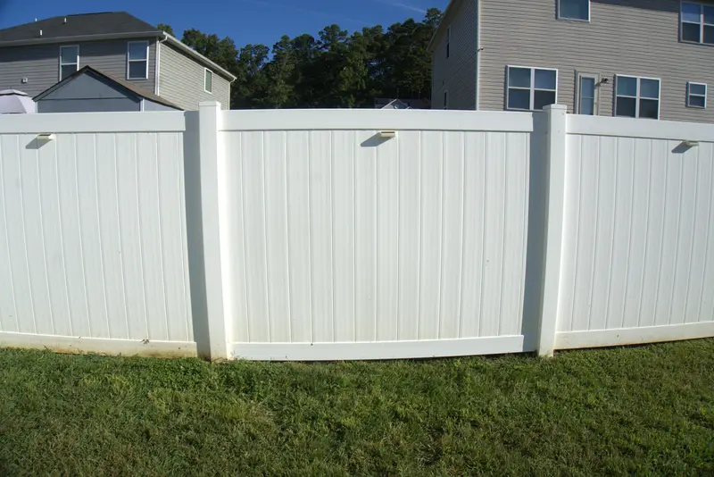 White vinyl privacy fence running along a back yard between two houses