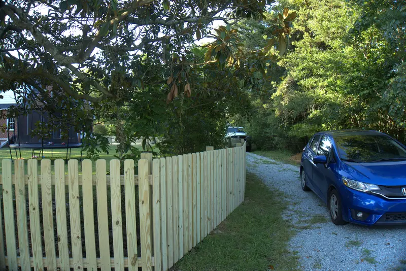 Wood picket fence along a gravel driveway